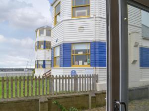a white and blue house in front of a fence at The View Old Coastguard Cottage in Tynemouth