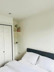 a bedroom with a bed with white sheets and a closet at Spacious flat on the High St in Beckenham