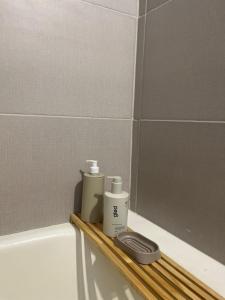 two bottles ofodorizers sitting on a wooden shelf in a bath tub at Andina Apart - Calm in the heart of Mendoza in Mendoza +14 photos