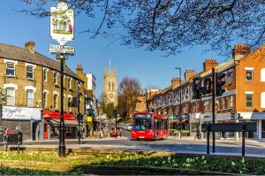 a red bus is driving down a city street at Flat on the High St in Beckenham