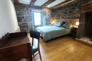 a bedroom with a bed and a stone wall at Gîte pour 9 personnes avec jardin à proximité du Puy Mary in Le Claux