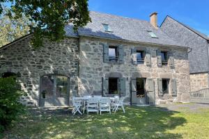 a stone house with a table and chairs in the yard at Gîte pour 9 personnes avec jardin à proximité du Puy Mary in Le Claux