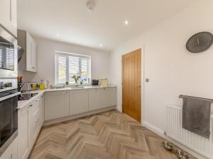 a kitchen with white cabinets and a clock on the wall at Curlew Retreat - Uk46780 in Ellington