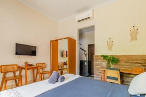 ein Schlafzimmer mit einem Bett und einem Tisch und einem Fernseher in der Unterkunft Kubu Deandari Guest House in Uluwatu