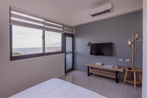 a bedroom with a bed and a television and a table at 大武民宿2195 in Shang-wu