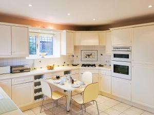 a kitchen with white cabinets and a table and chairs at Holly Barn in Selattyn