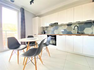 a kitchen with white cabinets and a table and chairs at Apartament nad Kwisą Mountain Aparts in Świeradów-Zdrój
