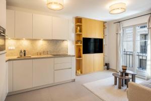 een keuken met witte kasten, een wastafel en een tv bij AC Apartment with 1 Bedroom for 4 Guests - Place des lices of Saint-Tropez in Saint-Tropez