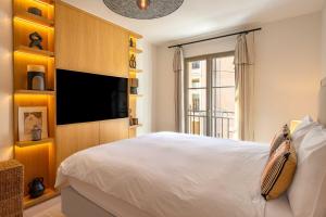 een slaapkamer met een groot bed en een flatscreen-tv bij AC Apartment with 1 Bedroom for 4 Guests - Place des lices of Saint-Tropez in Saint-Tropez