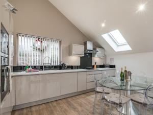 a kitchen with white cabinets and a glass table at Waterside Lodge Fifteen - Uk36708 in Southowram