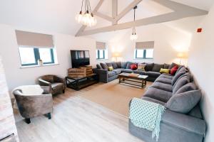 een woonkamer met een grijze bank en stoelen bij The Salt Retreatt By Birch Stays in Willaston