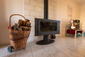 a fireplace with a tv and a basket of logs at Gite de la route du blé in Alluyes