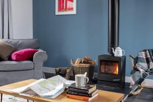 ein Wohnzimmer mit einem Sofa und einem Holzofen in der Unterkunft Cairn Cottage By Birch Stays in Stonehaven