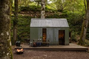 a green shed with a table and a fire at Glen Lodge And Abhainn Cottage By Birch Stays in Stonehaven +13 photos