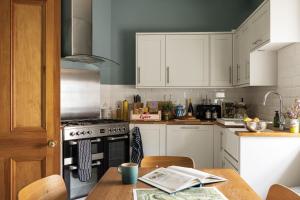 a kitchen with white cabinets and a stove top oven at Glen Lodge And Abhainn Cottage By Birch Stays in Stonehaven