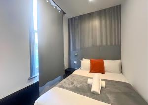 - une chambre avec un lit et un oreiller orange dans l'établissement Amsterdam Hotel, à Londres