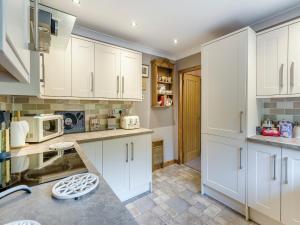 a kitchen with white cabinets and a counter top at Lochside View in Lochearnhead