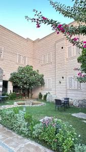 a large brick building with two chairs and flowers at فندق عنيزة الحديث in Unayzah
