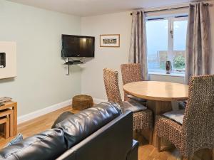 a living room with a leather couch and a table at Beudy Bach-Oh5 in Dihewid