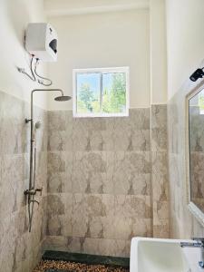 a bathroom with a shower with a sink and a window at STARK Villa in Talpe
