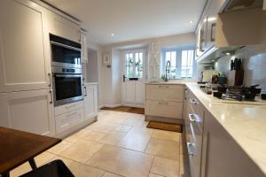 eine Küche mit weißen Schränken und einem Fliesenboden in der Unterkunft Weavers Cottage in Stow on the Wold