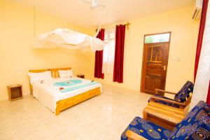 een slaapkamer met een bed en een stoel bij Severini Villas Zanzibar in Nungwi +57 foto's