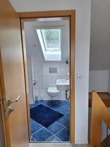 a bathroom with a toilet and a sink with a window at Haus Frank in Wehr