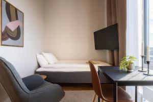 Kleines Zimmer mit einem Bett, einem Schreibtisch und Stühlen in der Unterkunft Forenom Aparthotel Luleå Västra Stranden in Luleå