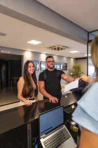 un hombre y una mujer parados en un mostrador con un portátil en Ilhéus Praia Hotel, en Ilhéus