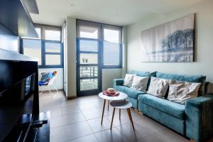 een woonkamer met een blauwe bank en een tafel bij LUXURY HOLIDAYS SUITES, Playa de los Cristianos in Los Cristianos