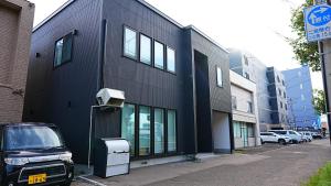 a black building with a security camera on a street at HOTELHOUSE Nekogoya Shindohigashi 新道東 in Sapporo
