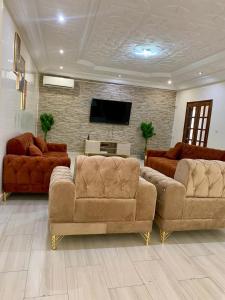 a living room with two couches and a flat screen tv at Les chandelles D'or in Thiès