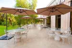 een terras met tafels, stoelen en parasols bij Palais Nouhass in Marrakesh