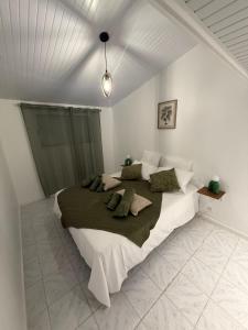 ein weißes Schlafzimmer mit einem großen Bett und grünen Kissen in der Unterkunft Villa JOLIS 4 chambres avec piscine en Guadeloupe in Les Abymes