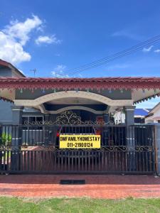 a house with a sign in front of a gate at Dmfamilyhomestay in Muar