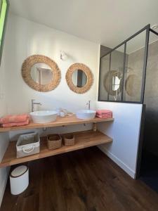 a bathroom with two sinks and mirrors on the wall at La Parenthèse in L'Ile d'Yeu