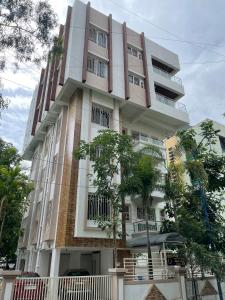 ein hohes weißes Gebäude mit Bäumen davor in der Unterkunft 4 BHK Duplex Flat at Baner, Pune in Pune