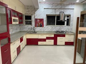 eine Küche mit roten und weißen Schränken und einem Waschbecken in der Unterkunft 4 BHK Duplex Flat at Baner, Pune in Pune + 50 Fotos