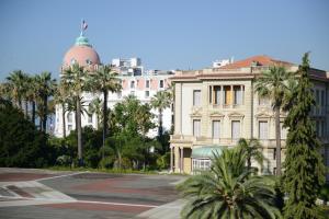 um grande edifício com palmeiras em frente em 29 Promenade des Anglais em Nice