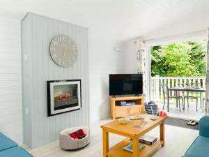 een woonkamer met een tafel en een klok aan de muur bij Merley Woodland Superior4 Lodge with Hot Tub in Wimborne Minster