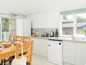 een keuken met witte kasten en een houten tafel bij Merley Woodland Superior4 Lodge with Hot Tub in Wimborne Minster +2 foto's