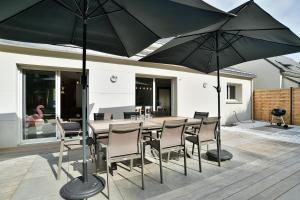 Le Vau PiardにあるLes 9 plages - Piscine privéeのテーブルと椅子、パラソルのあるパティオ