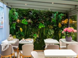 a room with a green wall with tables and chairs at Hotel Daumesnil-Vincennes in Vincennes