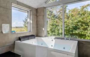 a bath tub in a bathroom with two windows at Lovely Home In Gørlev With Sauna in Reersø