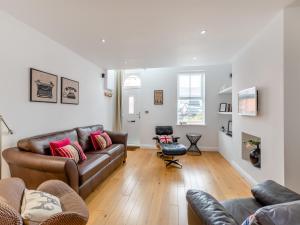a living room with a leather couch and a chair at Pebble Cottage in Cullercoats