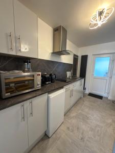 una cucina con mobili bianchi e un forno a microonde di Glenariff Forest Getaway a Glenariff
