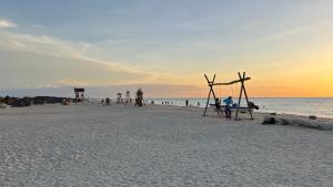- un groupe de personnes assises sur la plage au coucher du soleil dans l'établissement Hotel Wayira Beach by On vacation, à Ríohacha