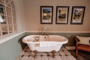 a bath tub in a bathroom with three pictures on the wall at The Ashford Arms in Bakewell