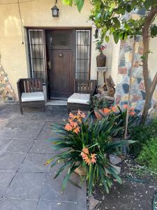 a porch with two benches and flowers in front of a door at Tu casa1 - Frente in General Pacheco