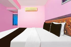 a bedroom with pink walls and a bed at Hotel O Trinetra Inn in Nagpur